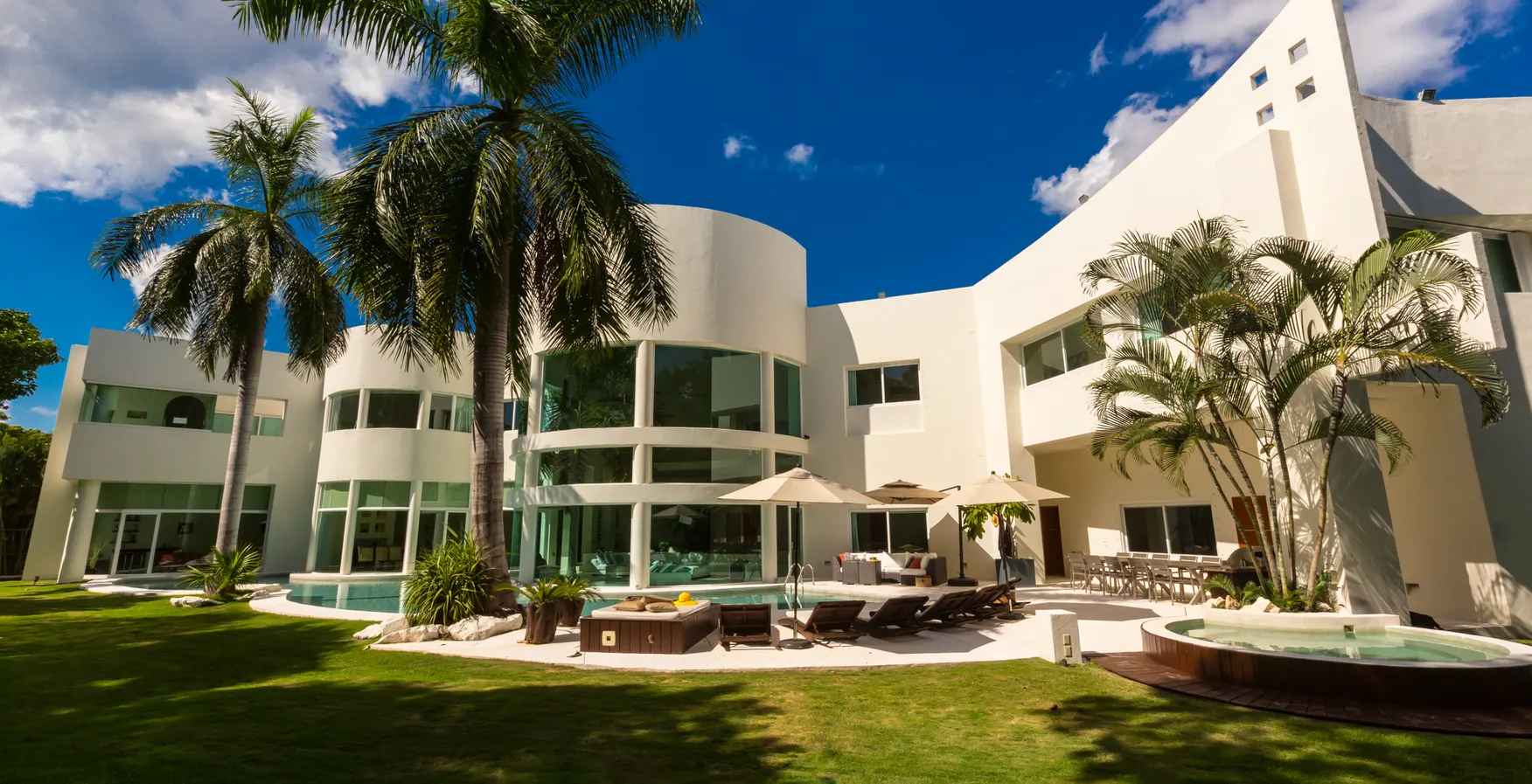 Villa Aqua's palm-shaded pool terrace under a bright blue sky